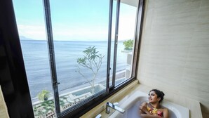 A person in a bathtub with a view of the sea and a balcony outside. - Capa Maumere (Maumere)