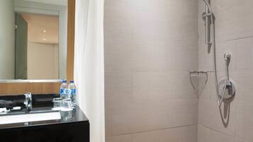 Un baño moderno con ducha, lavabo con espejo y tocador de madera.