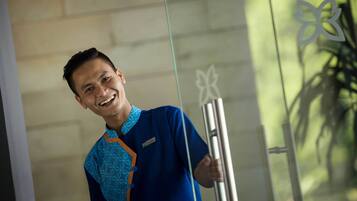 A person in a blue uniform holding a metallic object, standing in front of a glass wall with a butterfly design.