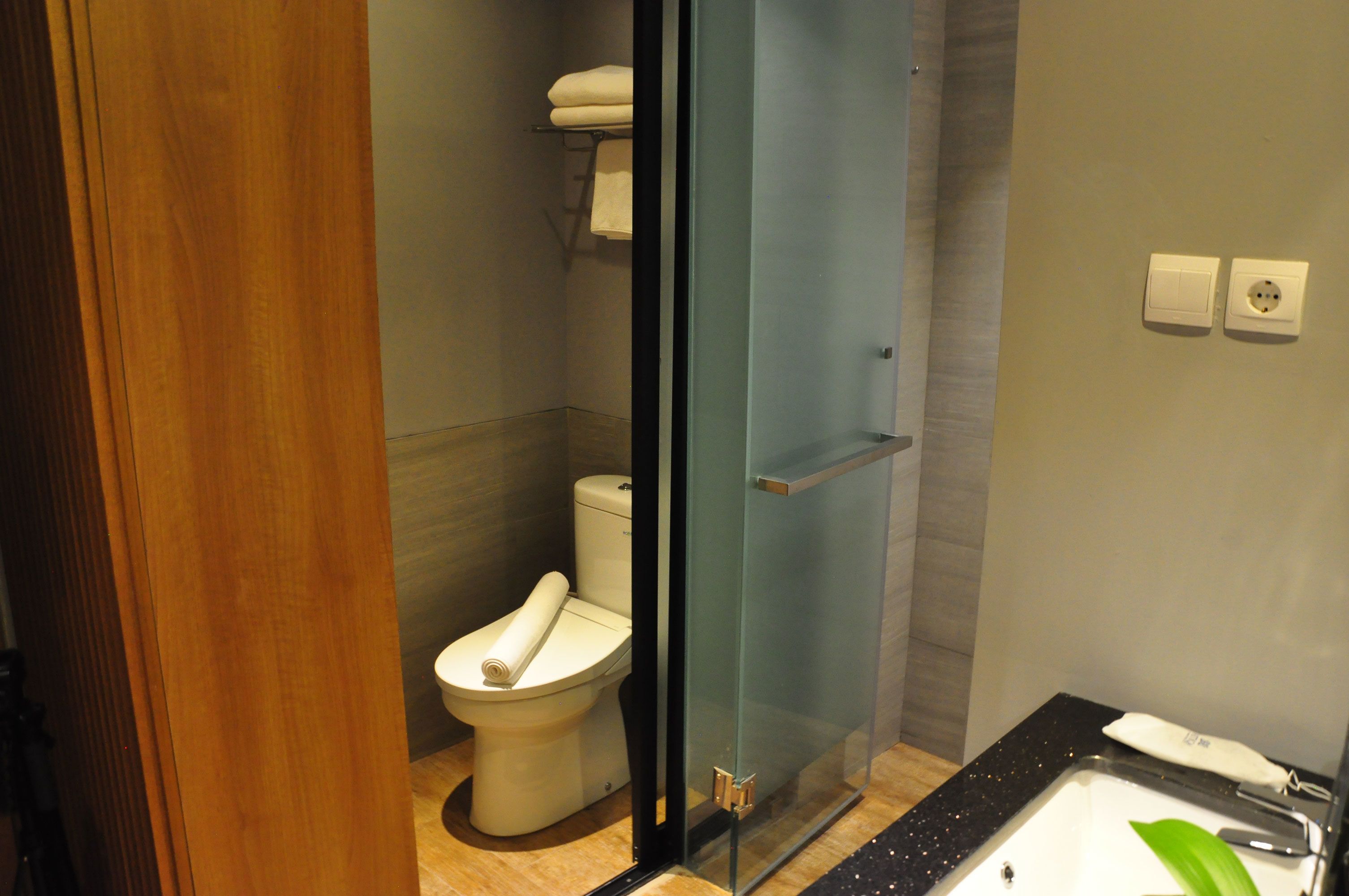 Ein modernes Badezimmer mit Duschkabine aus Glas, Toilette und Waschbecken mit Spiegel.