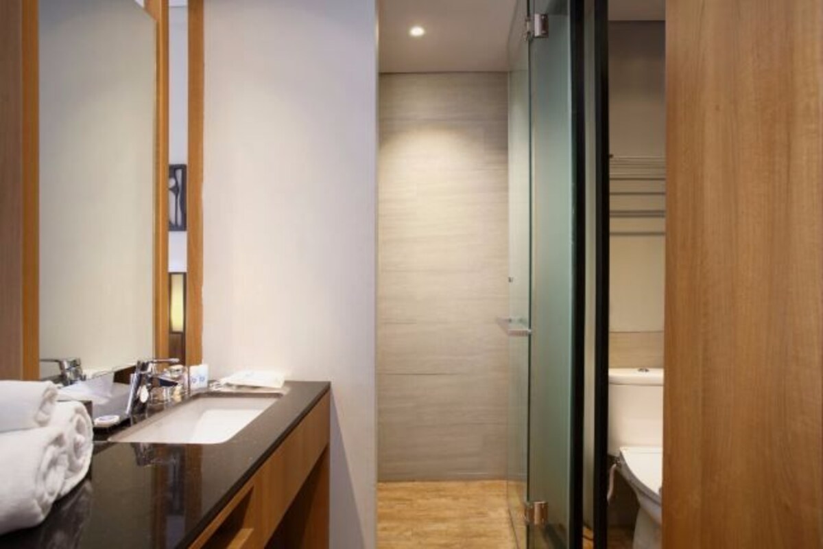 A modern bathroom with a dark countertop sink, a mirror, and a glass shower enclosure.