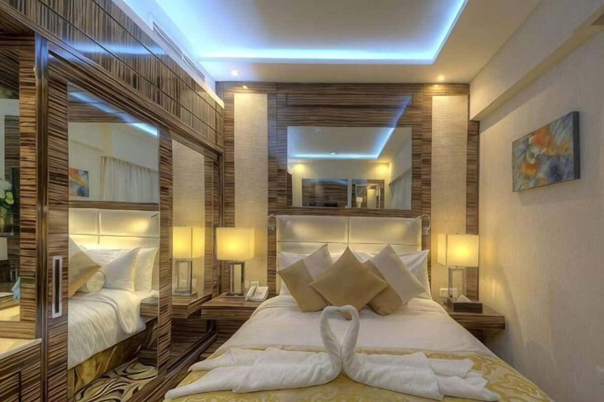 A hotel room with a large bed, two nightstands, a mirror, and a painting on the wall.