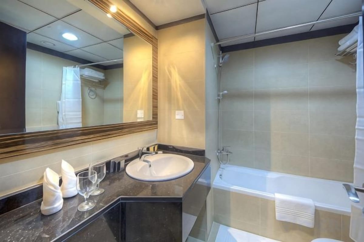 A modern bathroom with a large mirror, a sink, a bathtub, and a shower.