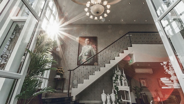 A grand staircase with a chandelier, framed portrait, and decorative elements like a birdcage and statues. - Club Tree Hotel (Songkhla)