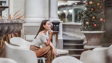 Une personne est assise à une table dans un intérieur, avec un sapin de Noël en arrière-plan.