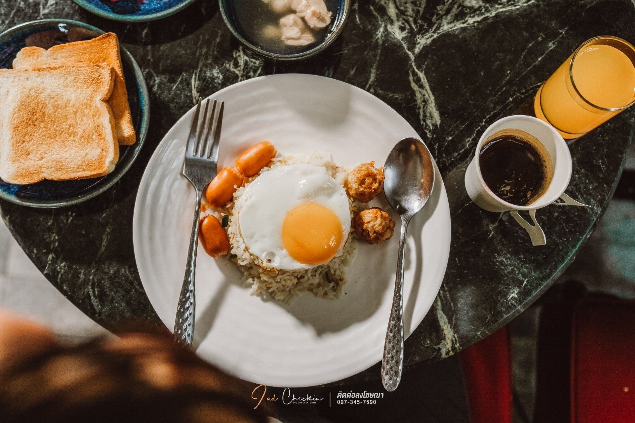 Un plato de desayuno con huevo frito, salchichas y tostadas sobre una mesa de mármol.