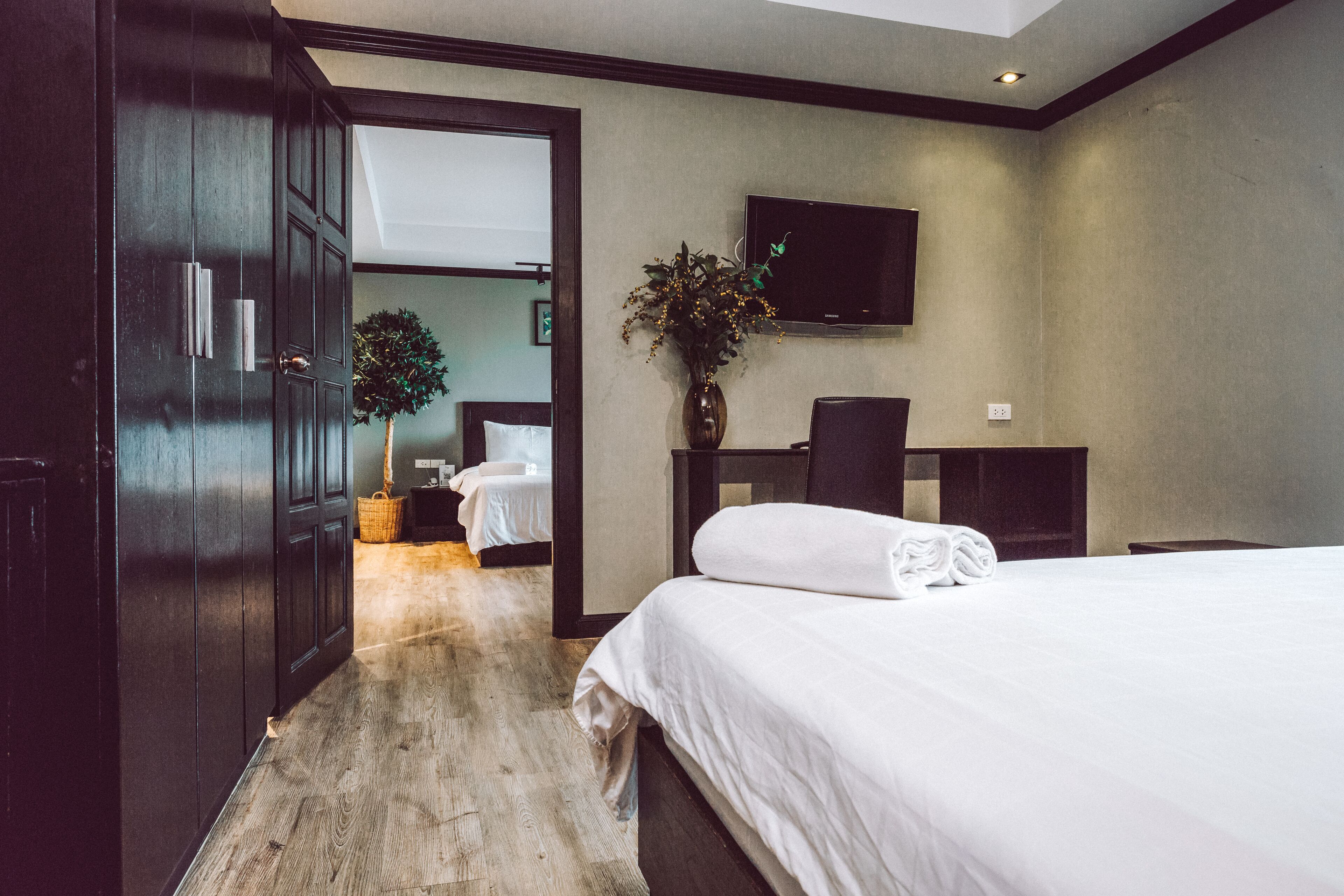 Ein Hotelzimmer mit einem großen Bett, einem Schreibtisch, einem Fernseher und einer Pflanze.