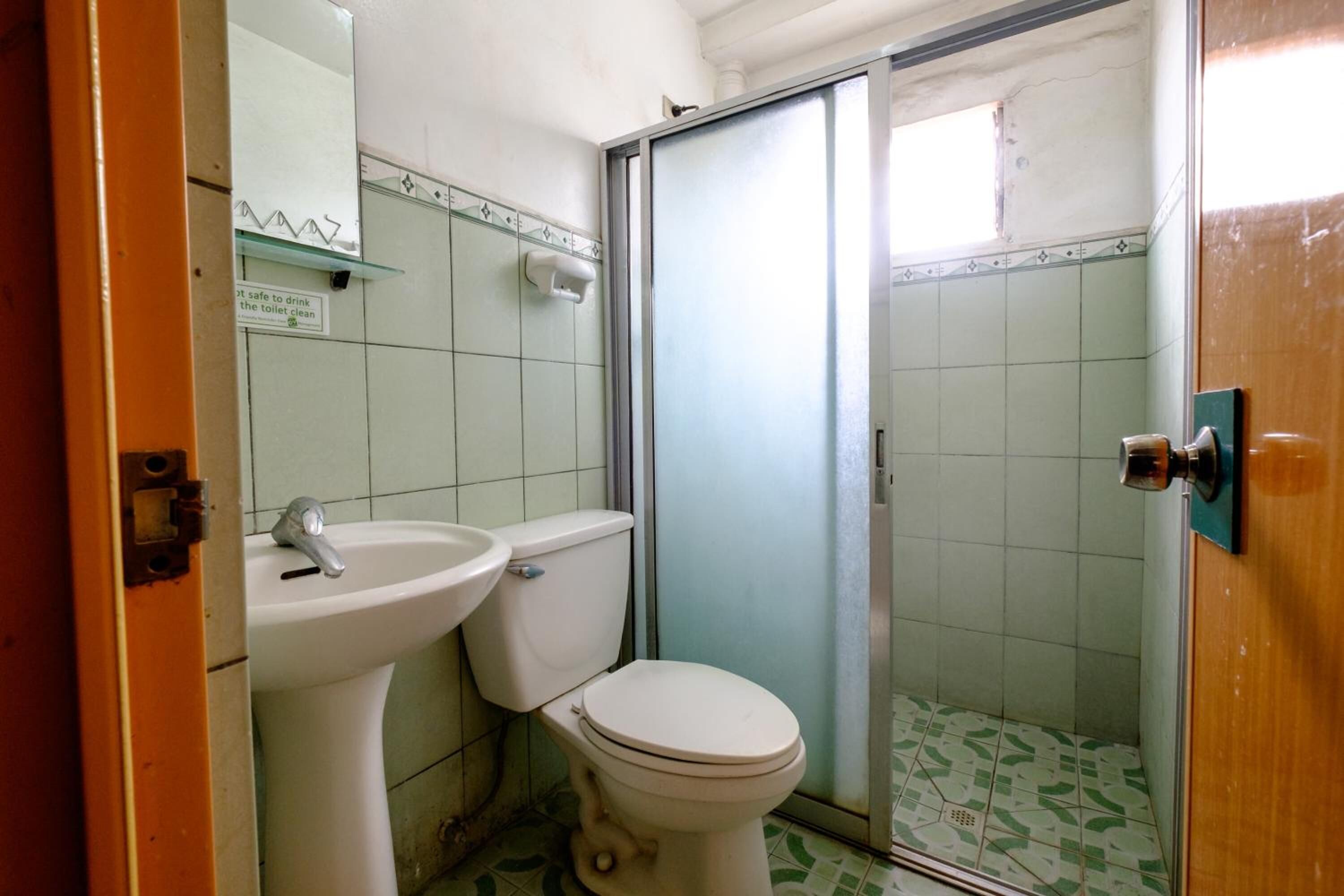 Et badeværelse med toilet, håndvask og bruseområde.