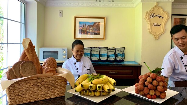 Una encimera de cocina de hotel con pan, plátanos y uvas.