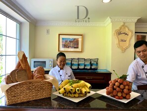 A hotel kitchen counter with bread, bananas, and grapes displayed.
