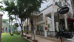 Un hotel boutique con un jardín cuidado, un sendero pavimentado y una motocicleta estacionada afuera.