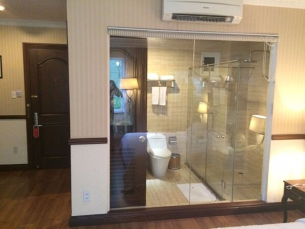 A hotel bathroom with a glass-enclosed shower, a toilet, and a sink.