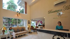 Un hall de hotel con mostrador de recepción, un sofá y un ventanal grande.