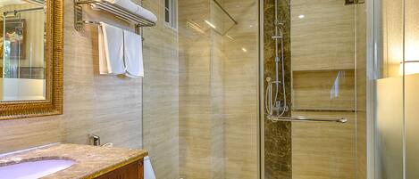 Un baño moderno con tocador de mármol, cabina de ducha de vidrio y retrete.
