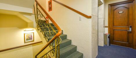 A staircase with green carpeted steps, a wooden handrail, and a wall-mounted picture frame.