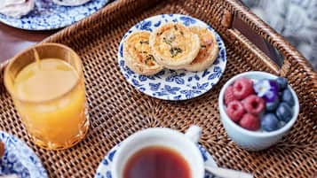 A breakfast tray with pastries, a glass of orange juice, a cup of tea, and a bowl of berries.