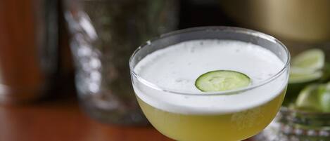 A cocktail in a stemmed glass with a lime garnish on a wooden table.