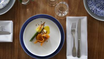 A dining table with a blue-rimmed plate, a fork, and a knife on a white napkin.