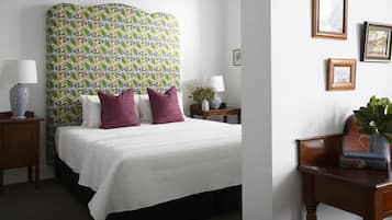 A neatly made bed with a patterned headboard, two bedside tables with lamps, and a small bedside plant.