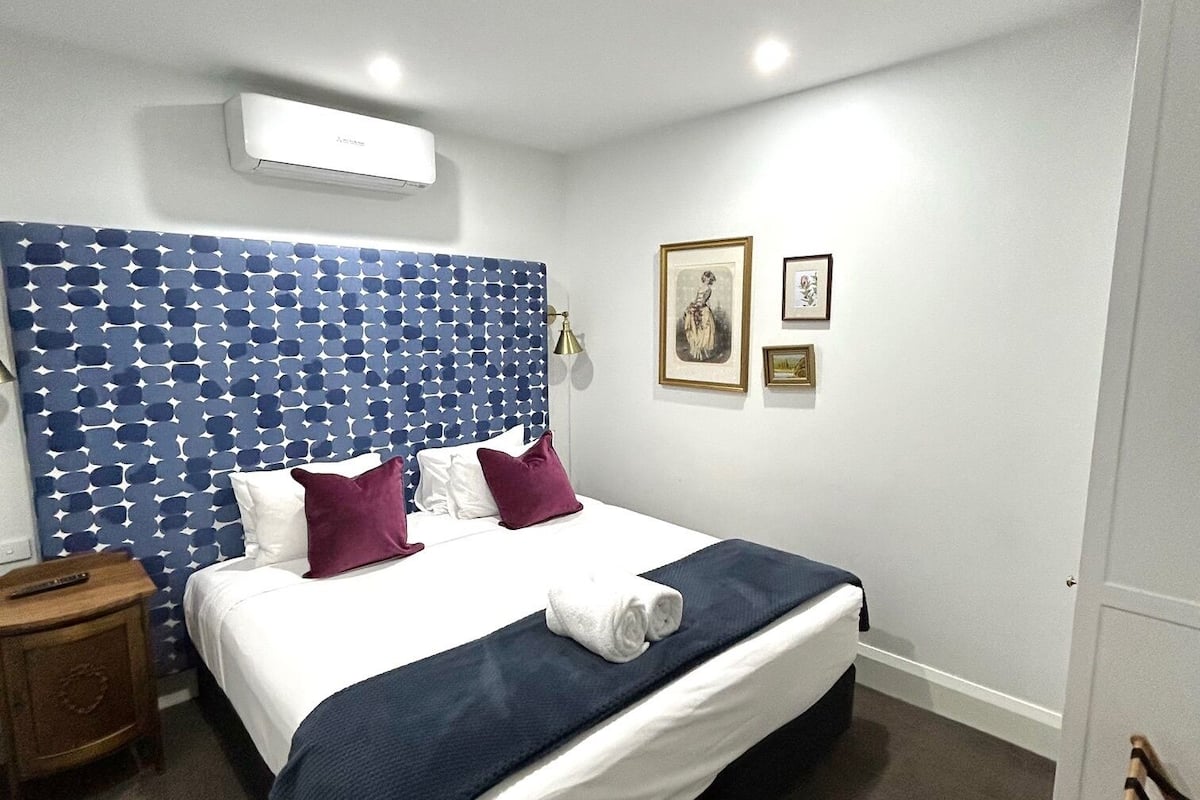 Habitación de hotel con cama, mesita de noche, armario y puerta.