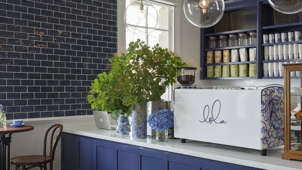 A kitchen with a brick wall, a potted plant, a laptop, and a display case with pastries. - The Provincial Boutique Hotel (Ballarat)