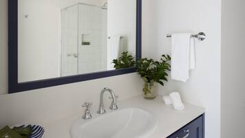 Un bagno con uno specchio grande, un lavandino bianco, un armadietto blu scuro e un porta asciugamani.