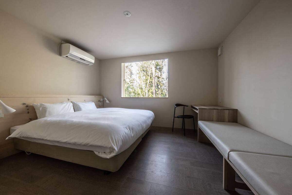 Un dormitorio con cama, escritorio y banco.