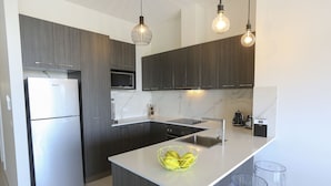 Una cocina moderna con alacenas de madera oscura, una isla blanca y un microondas integrado.