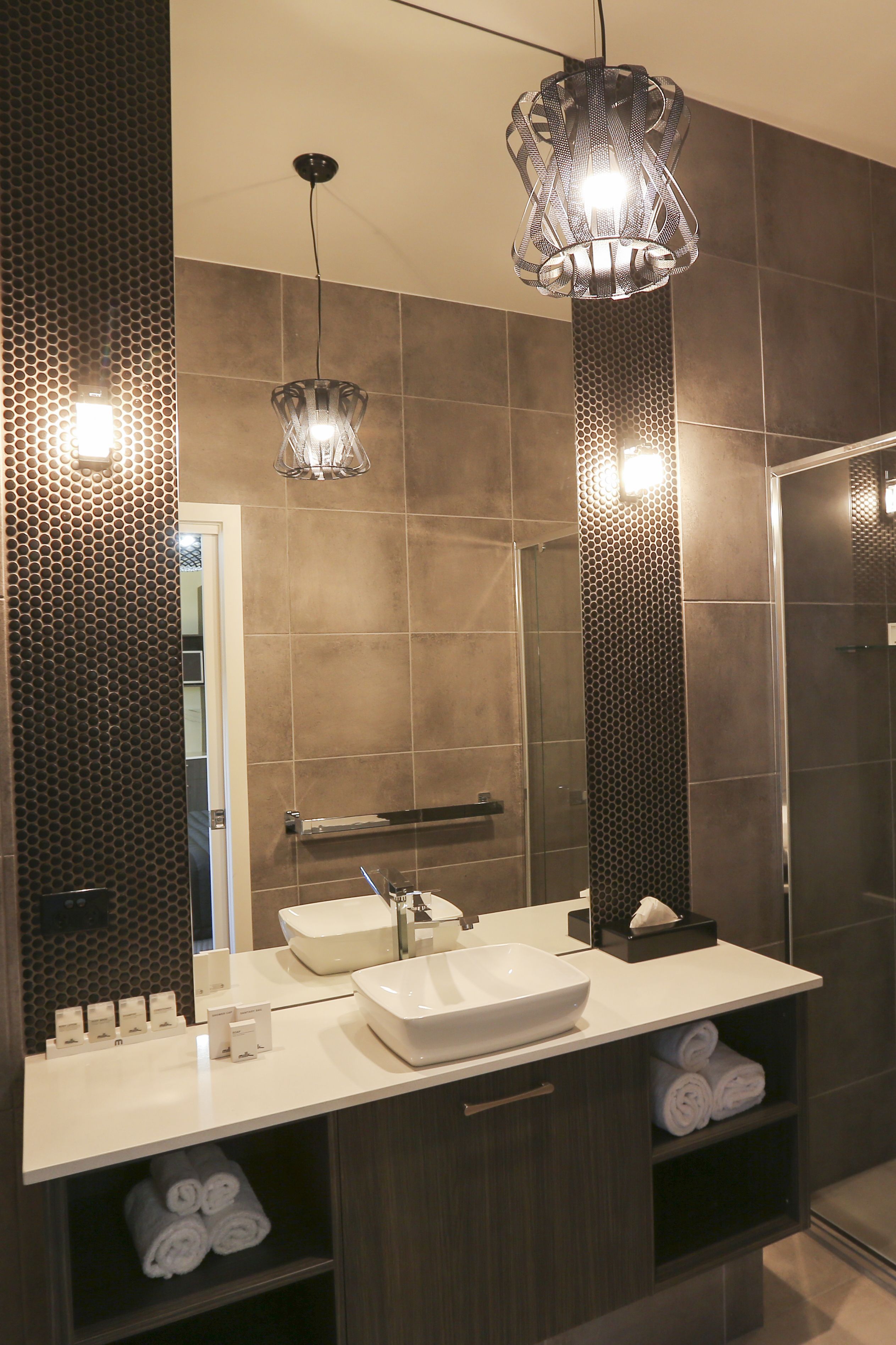 A modern bathroom with a large mirror, a vessel sink, and two pendant lights.