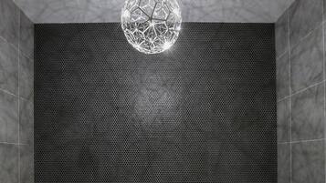 Un bagno moderno con una vasca freestanding, una lampada a sospensione geometrica e un muro testurizzato.
