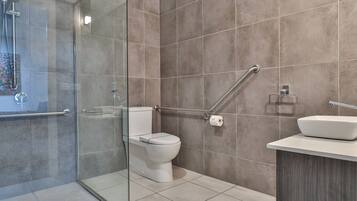 Un baño moderno con cabina de ducha de vidrio, inodoro blanco y lavamanos sobre encimera.