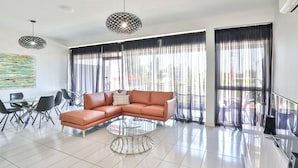 Una sala moderna con un sofá seccional, una mesa de centro de vidrio y un comedor con sillas y una mesa.