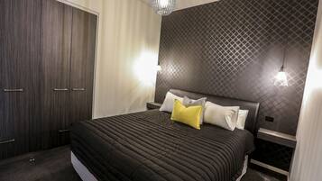 A bedroom with a large bed, a wardrobe, and a patterned wall.