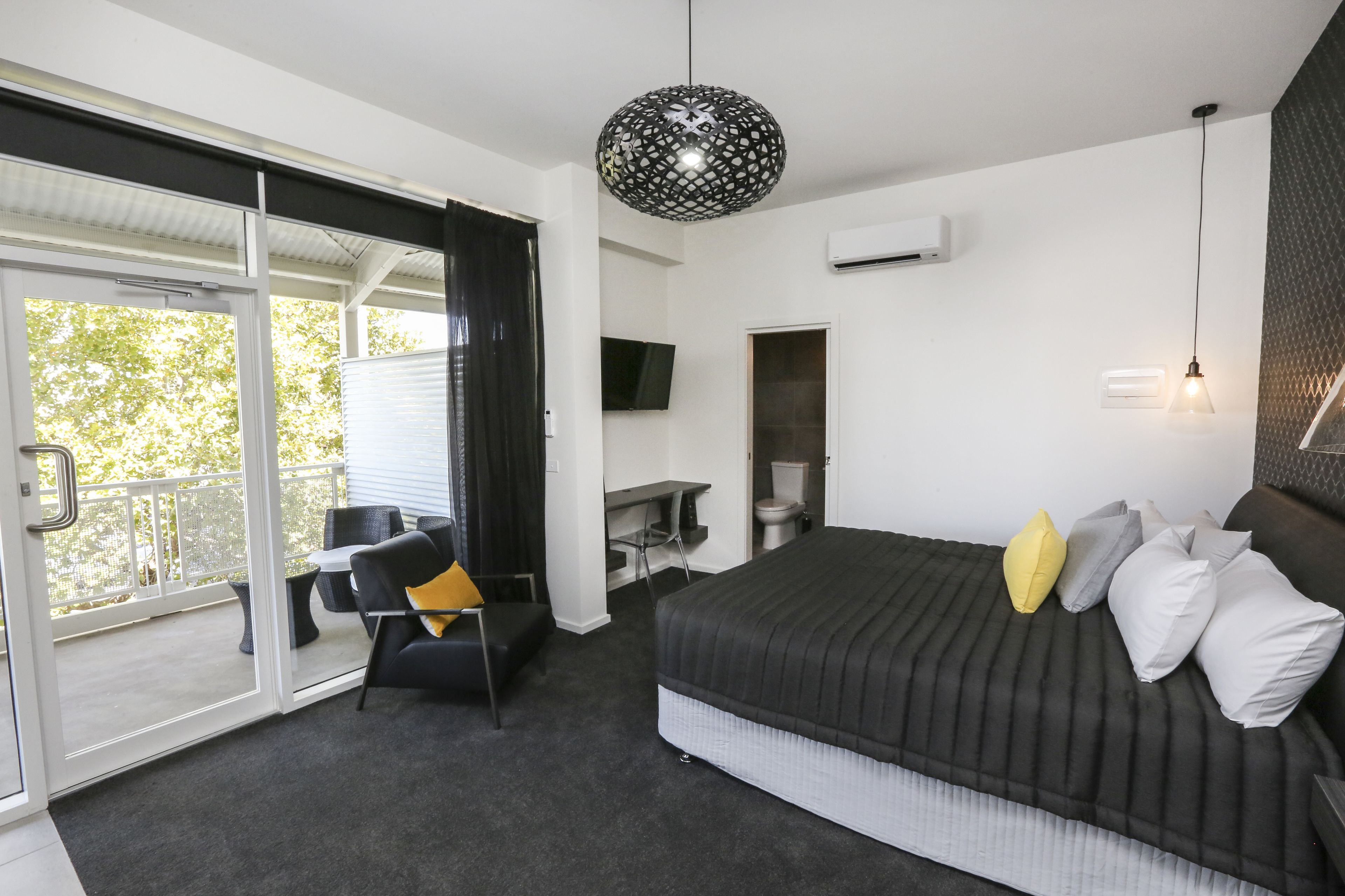 Une chambre avec un lit, un bureau, une chaise et un balcon.