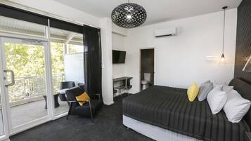 A bedroom with a bed, a desk, a chair, and a balcony.
