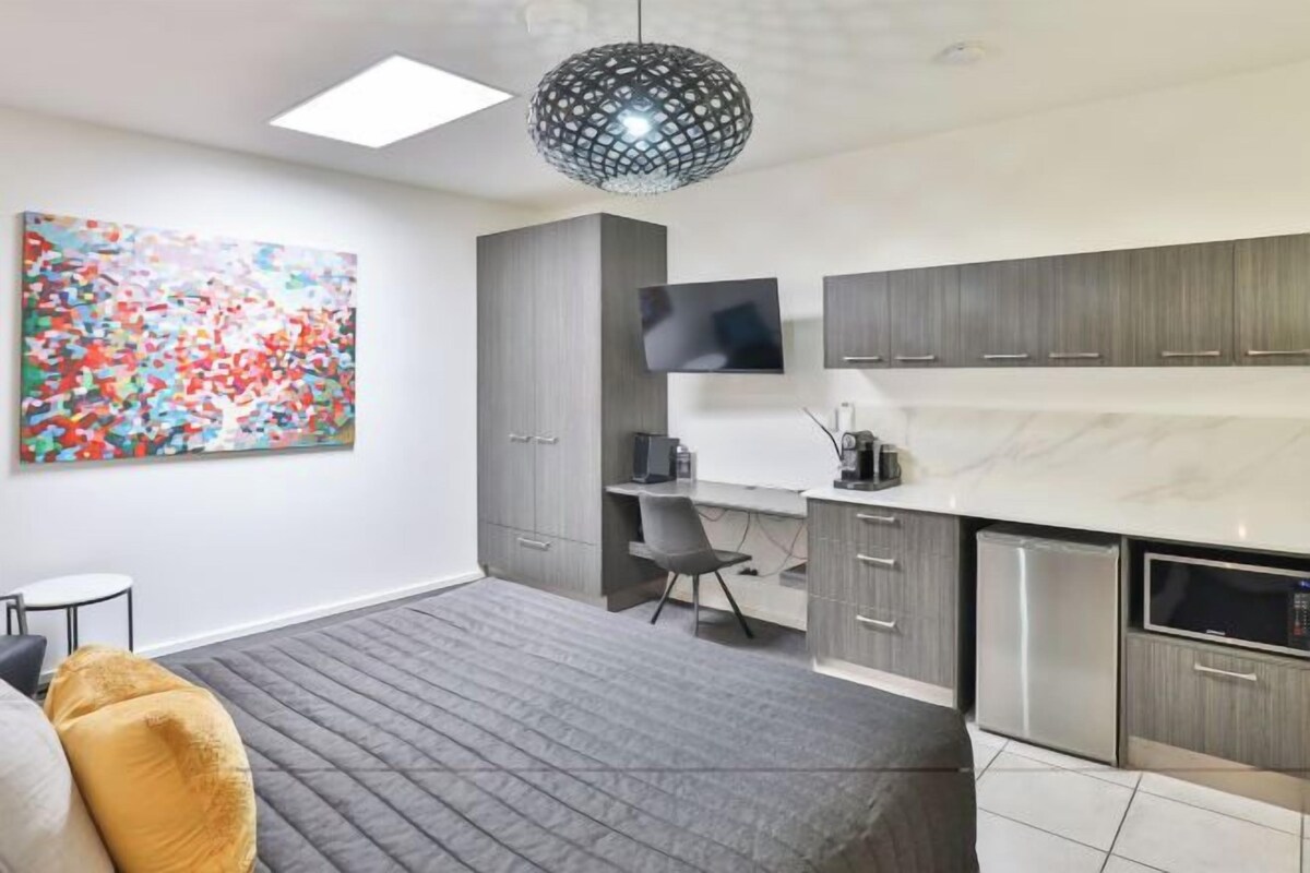 Un dormitorio moderno con cama, escritorio y kitchenette.