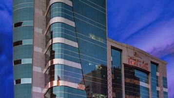 A modern hotel with a curved glass facade and a sign for 'DEIRA SUITES'.