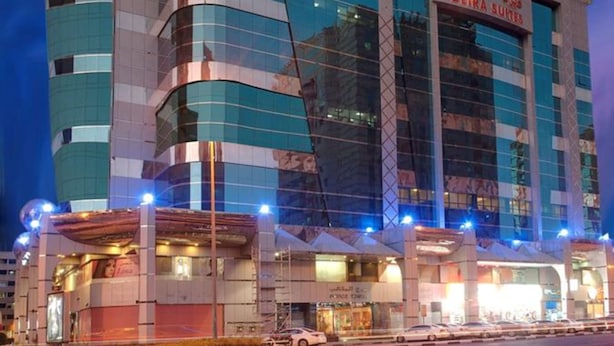 Een modern hotel met een gebogen gevel, meerdere verdiepingen en een opvallend bord met 'DEIRA SUITES'.