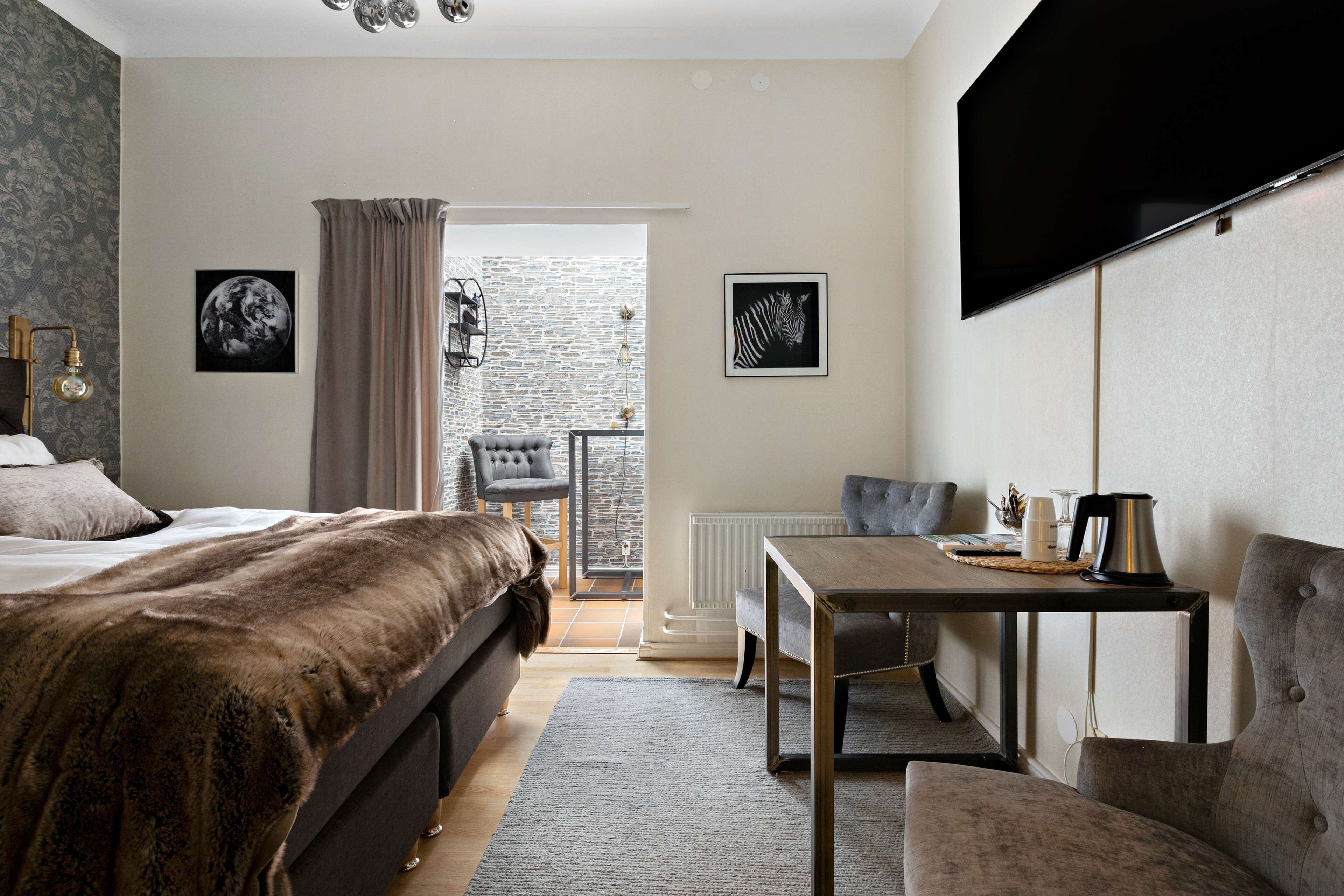 Une chambre avec un grand lit, un bureau et un téléviseur. Une fenêtre offre une vue sur l’extérieur.