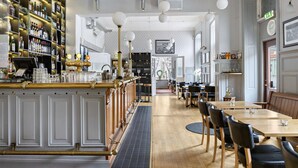 A bar area with a long counter, shelves with bottles, and a seating area with tables and chairs. - Nora Stadshotell, Sure Hotel Collection by Best Western (Nora)