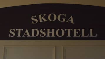 A sign with the text "SKOGA STADSHOTELL".