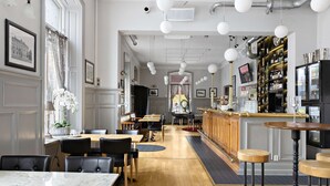 A restaurant with marble tables, black leather chairs, a bar area with stools, and a wooden floor. - Nora Stadshotell, Sure Hotel Collection by Best Western (Nora)
