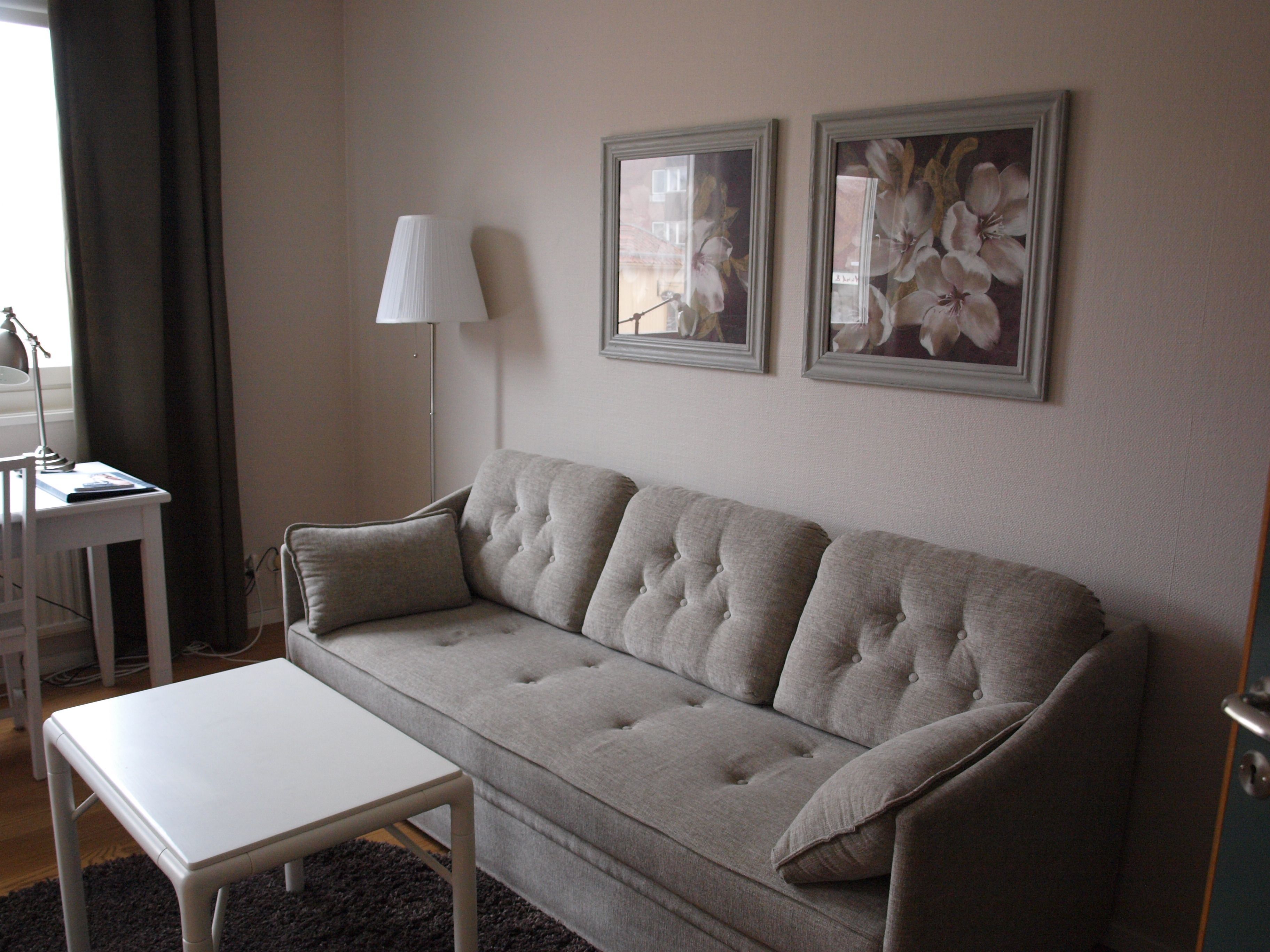 A living room with a grey sofa, a white coffee table, and two framed floral paintings on the wall.