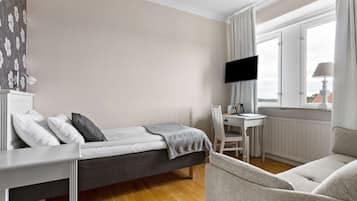 A modern bedroom with a bed, a desk, and a TV.
