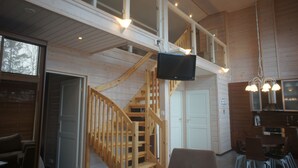 Un interior de madera con una escalera, un televisor de pantalla plana y un comedor.