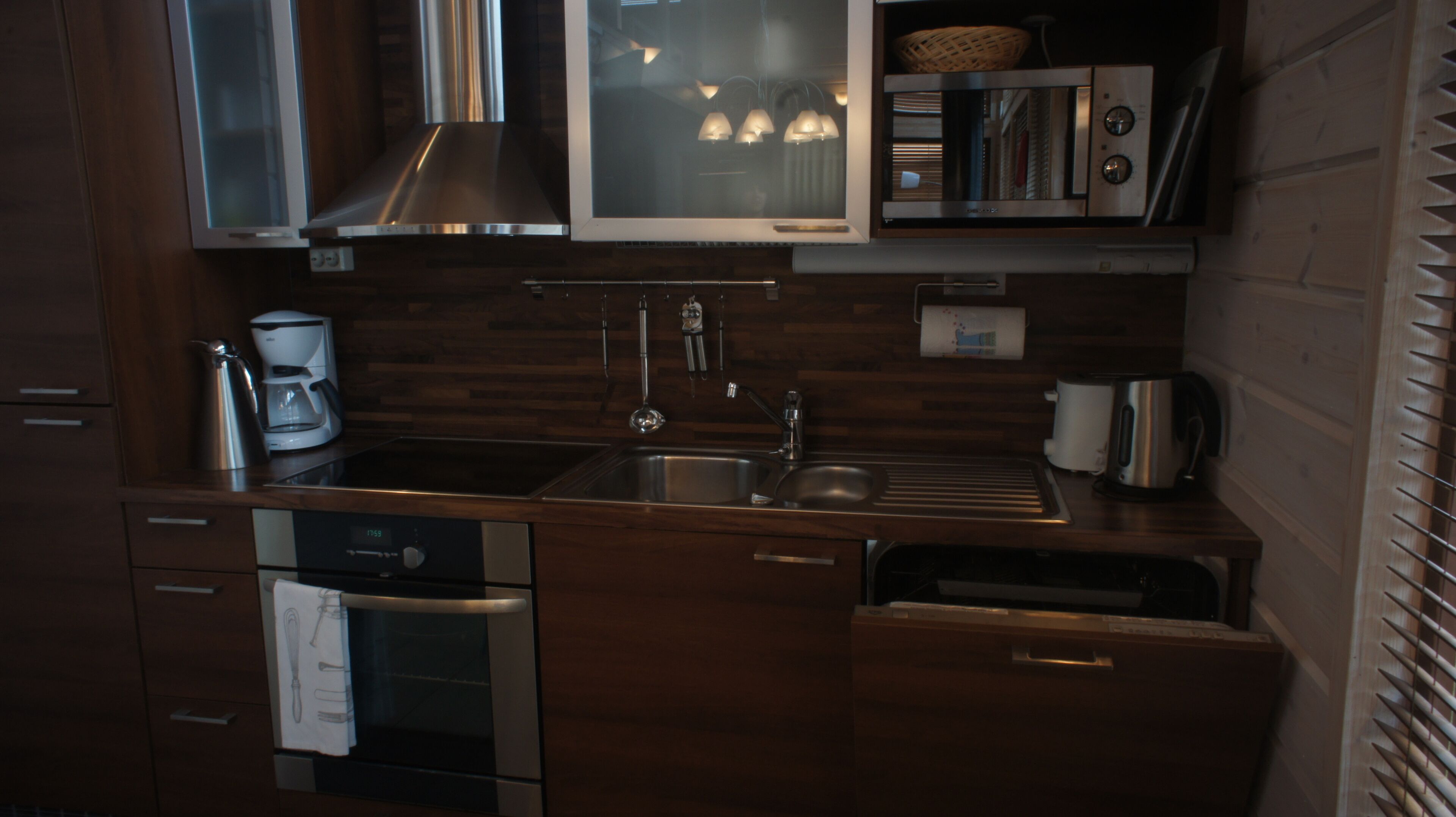 A modern kitchen with stainless steel appliances, wooden cabinetry, and a built-in microwave.