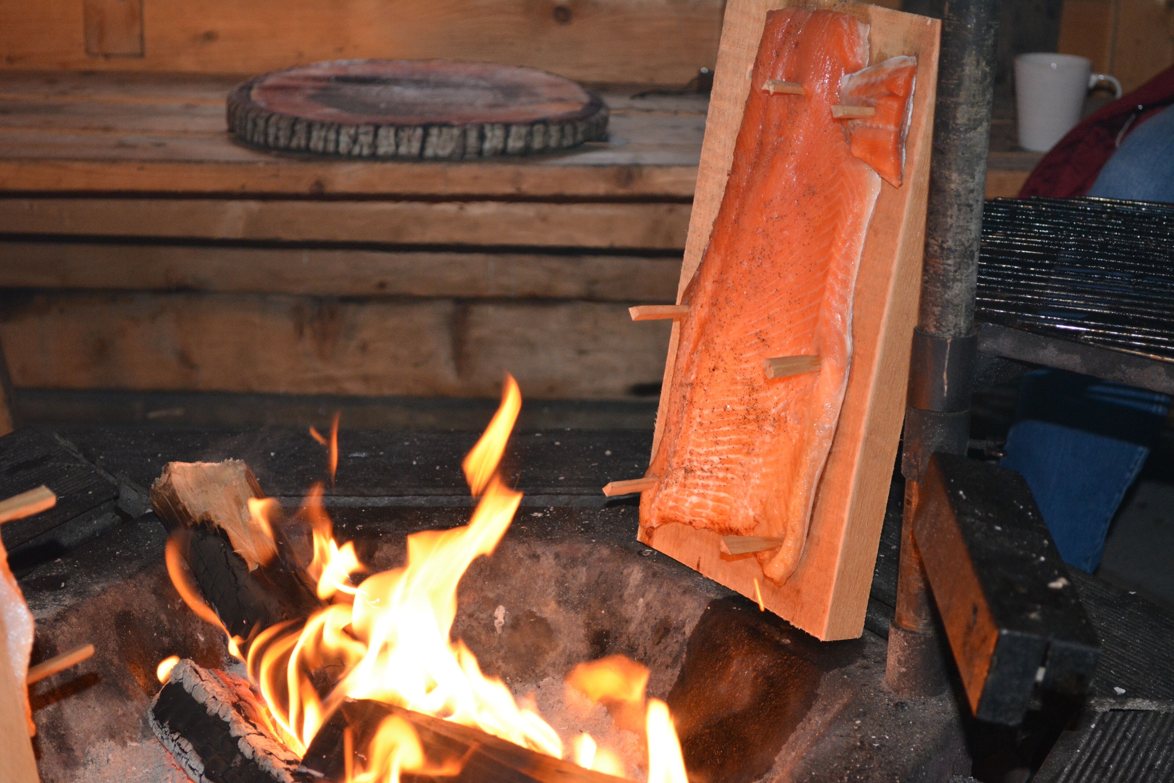 Chimenea con leña ardiendo y un trozo de madera ahumándose.