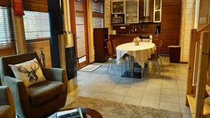Una sala de estar acogedora con chimenea, un comedor con mesa redonda y una cocina con armarios de madera.