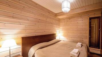 A wooden-paneled room with a bed, bedside lamp, and a door.