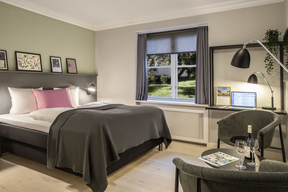 A modern bedroom with a bed, bedside table, and a desk with a computer.